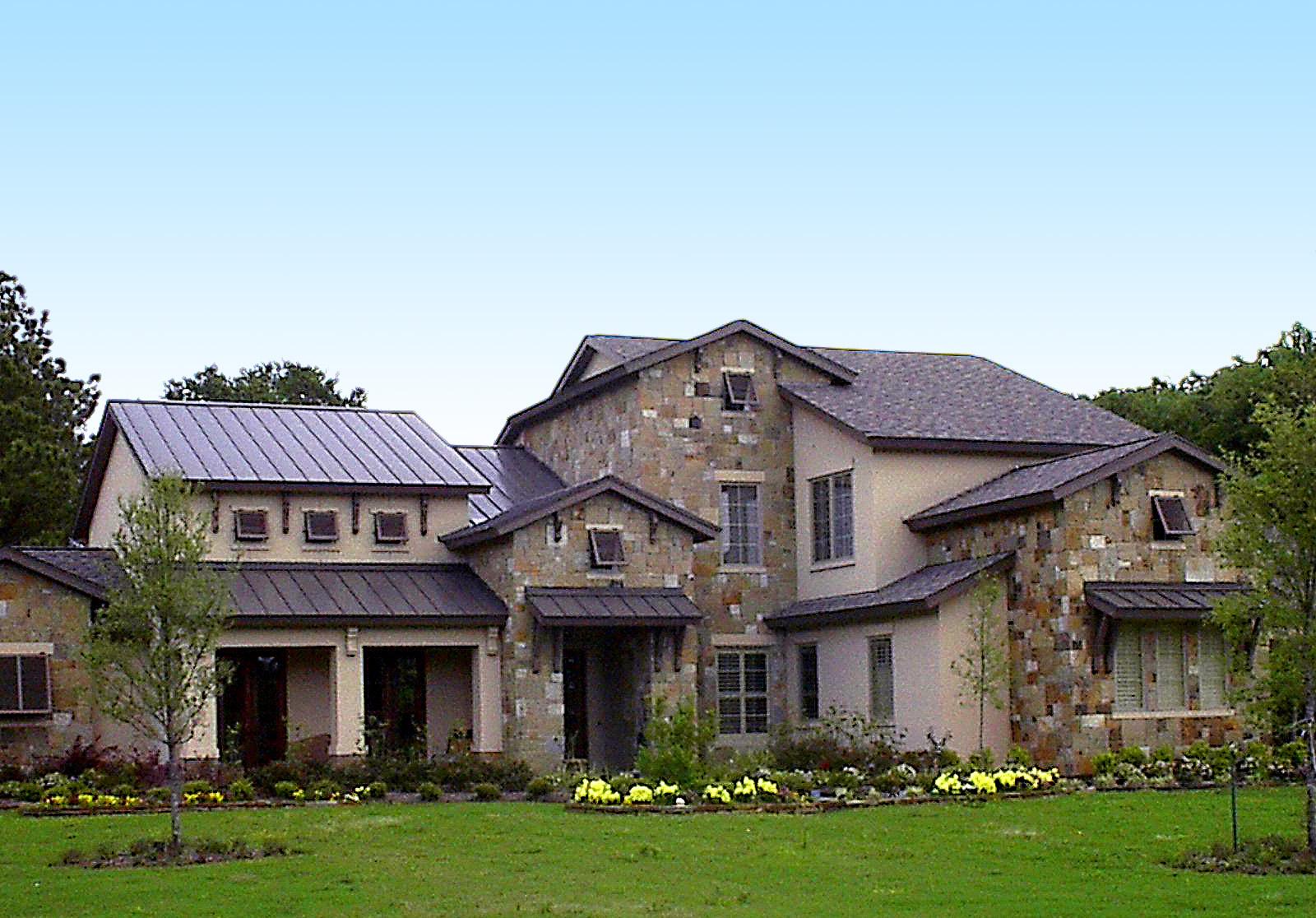 House plan exterior featuring stone facade, metal roofs, gables, dormers, and covered entryways with columns.