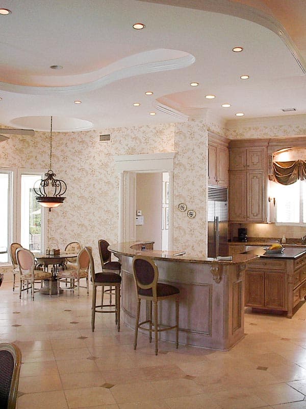 Kitchen and dining area with curved bar, island, and decorative ceiling detail.