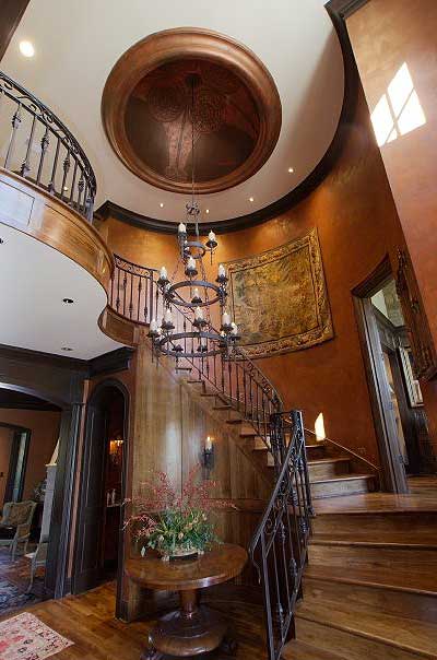 Grand Foyer: Curved staircase with ornate railing, large chandelier, domed ceiling with detailed mural, and tapestry wall art.