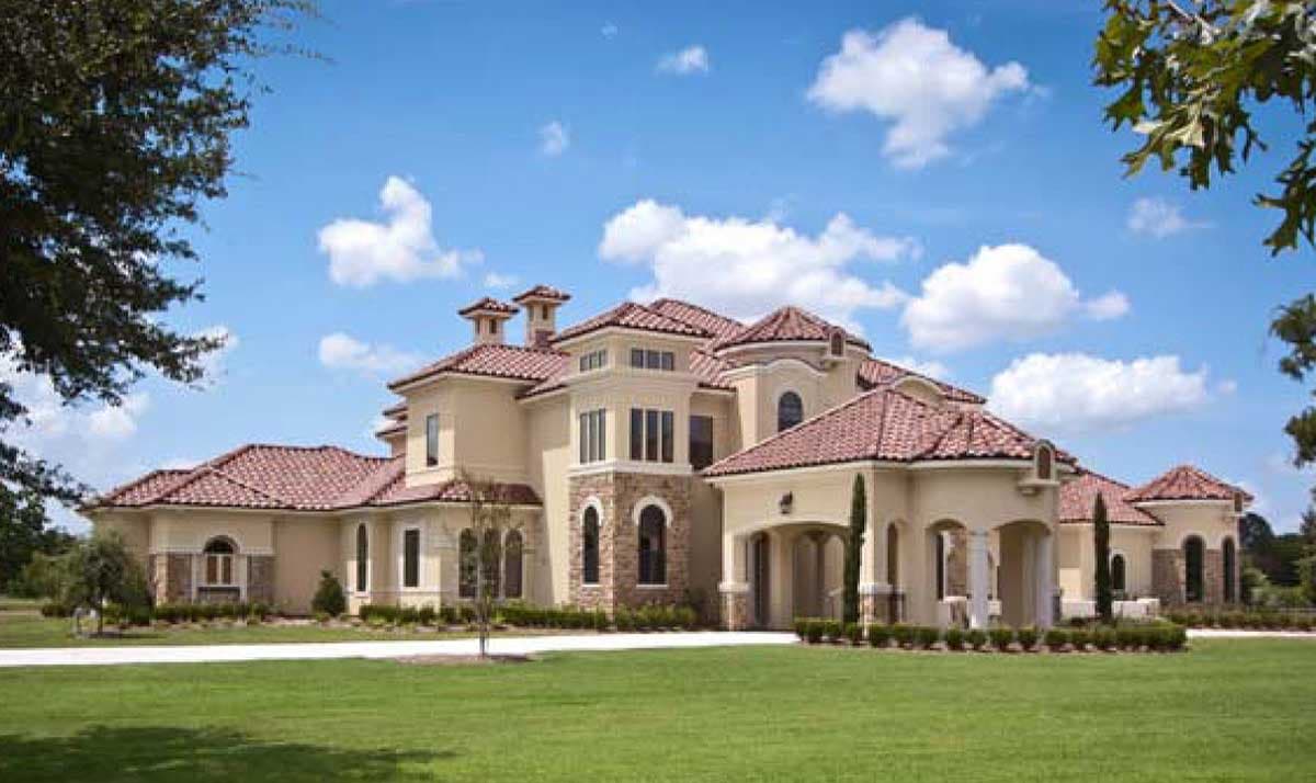 House plan exterior featuring a Mediterranean style with red tile roofs, arched windows, and a covered portico.