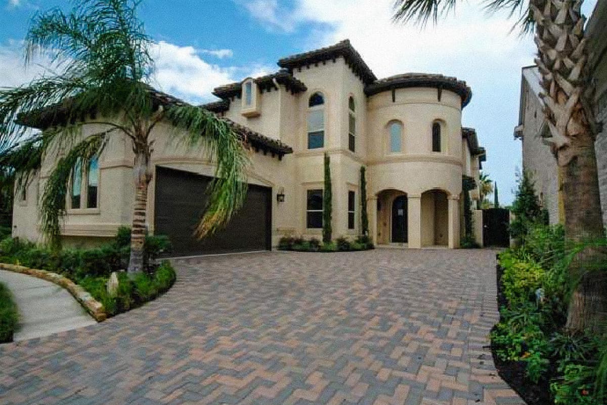 House plan exterior featuring a two-story stucco design with a rounded turret, arched entry, tiled roof, and a triple garage.
