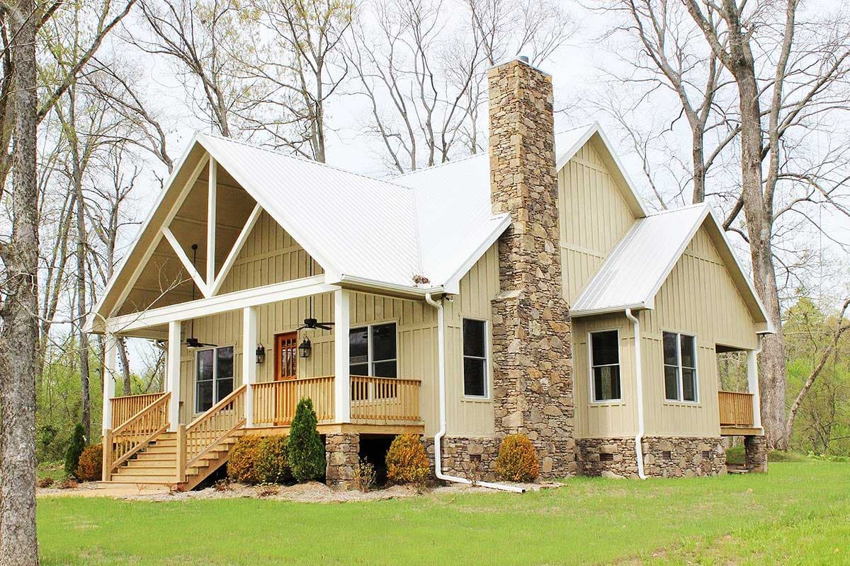 House plan exterior: Modern Farmhouse style, one-story, with gabled roof, exposed rafter tails, stone chimney, and wraparound porch.