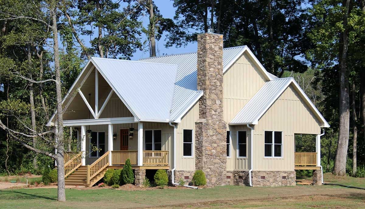 House plan exterior of a two-story Modern Farmhouse with a gabled roof, stone chimney, and wraparound porch.