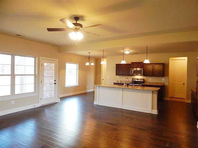 Open concept living area with kitchen island, dark wood cabinets, and access to a door with glass panes.
