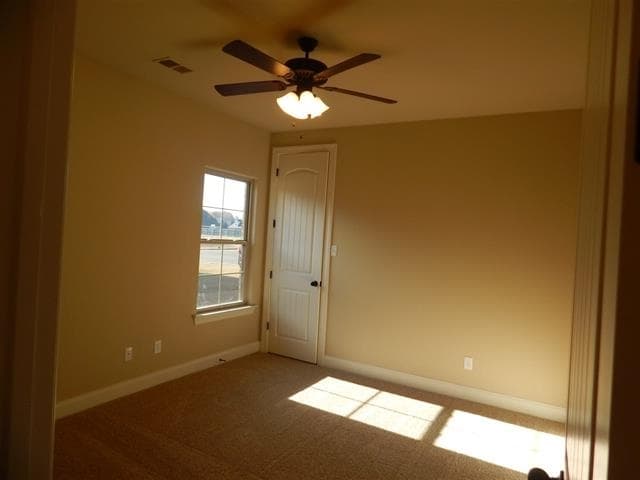 Interior view of an empty room with a ceiling fan, single window, and paneled door.