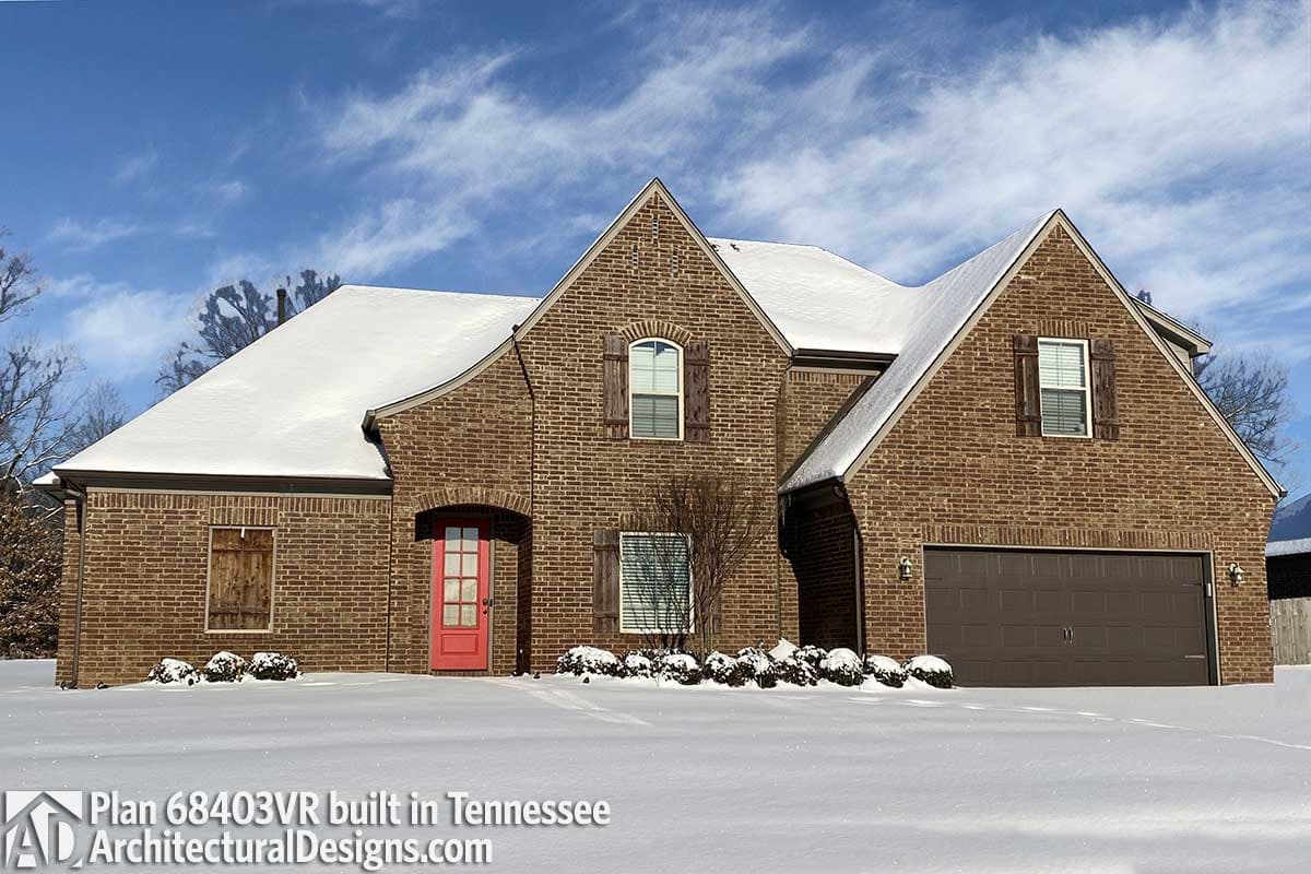 House plan exterior: Two-story brick home with arched entry, prominent gables, decorative shutters, and attached garage.