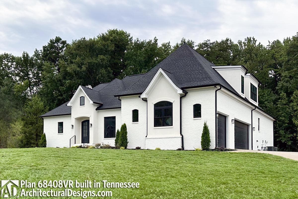House plan exterior: Modern style, single-story with white brick, black roof, arched windows, and a two-car garage.