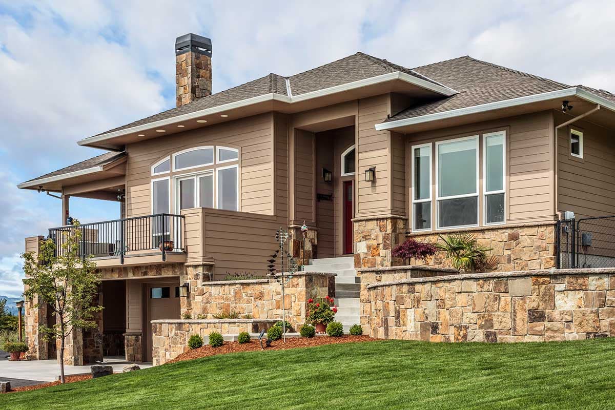 House plan exterior with stone accents, multiple gables, a covered balcony, and a prominent stone chimney.