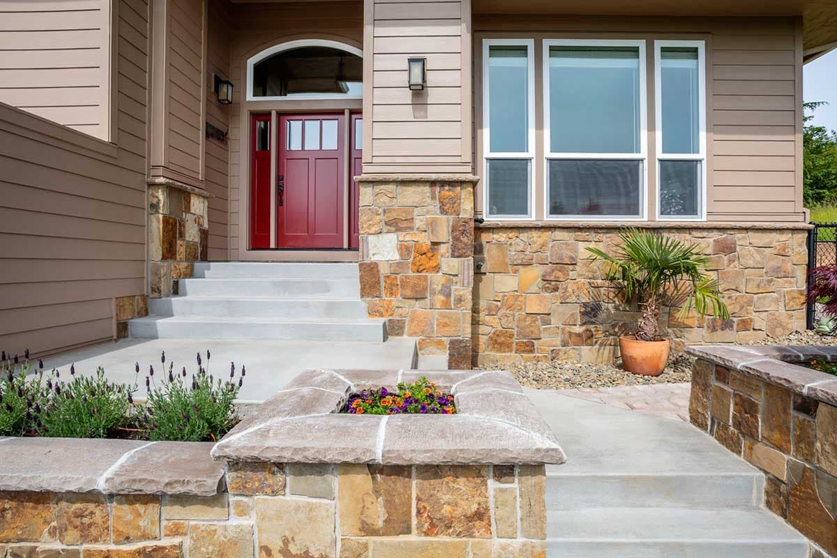 House plan exterior with stone accents, a red double door entry with arched transom window, and large casement windows.