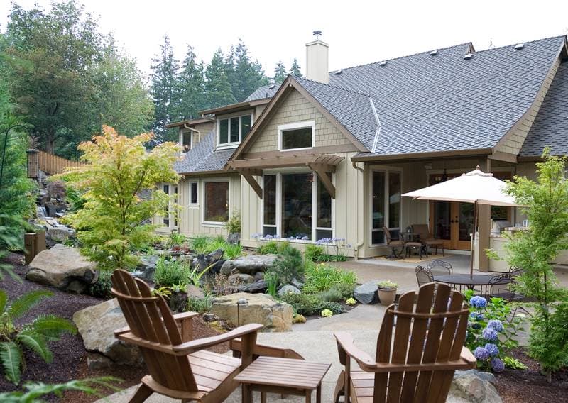 House plan exterior: Two-story home with gables, dormers, a covered patio, and a sloped roofline.