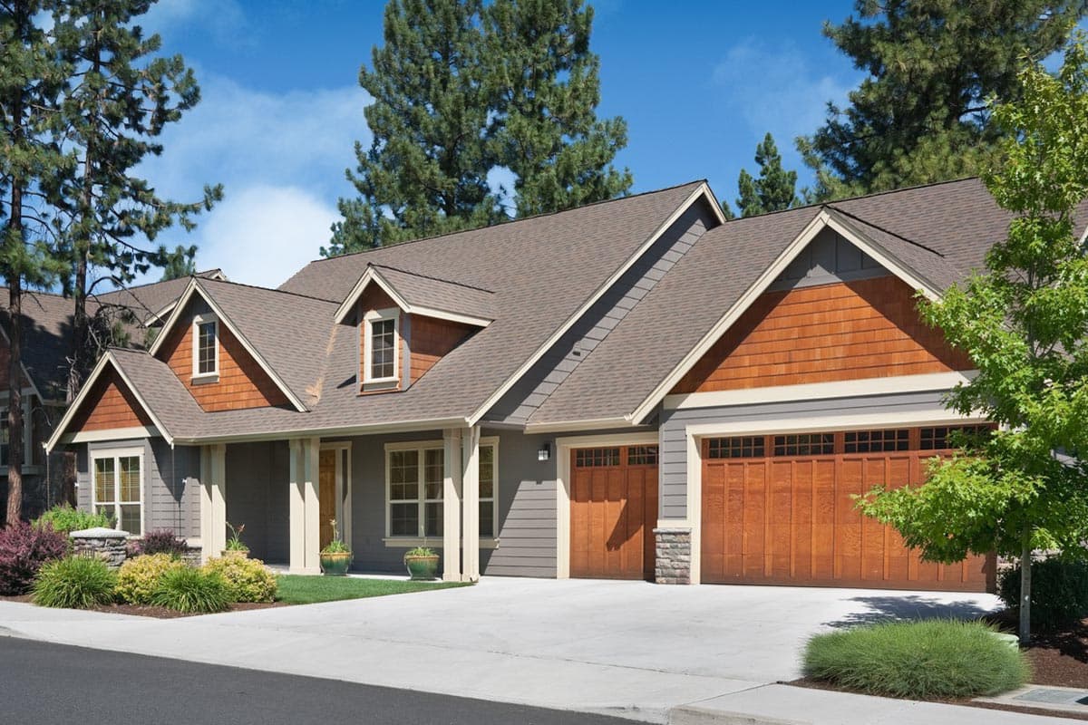 Craftsman style house plan exterior with dormers, prominent gables, wood shingle accents, and a three-car garage.