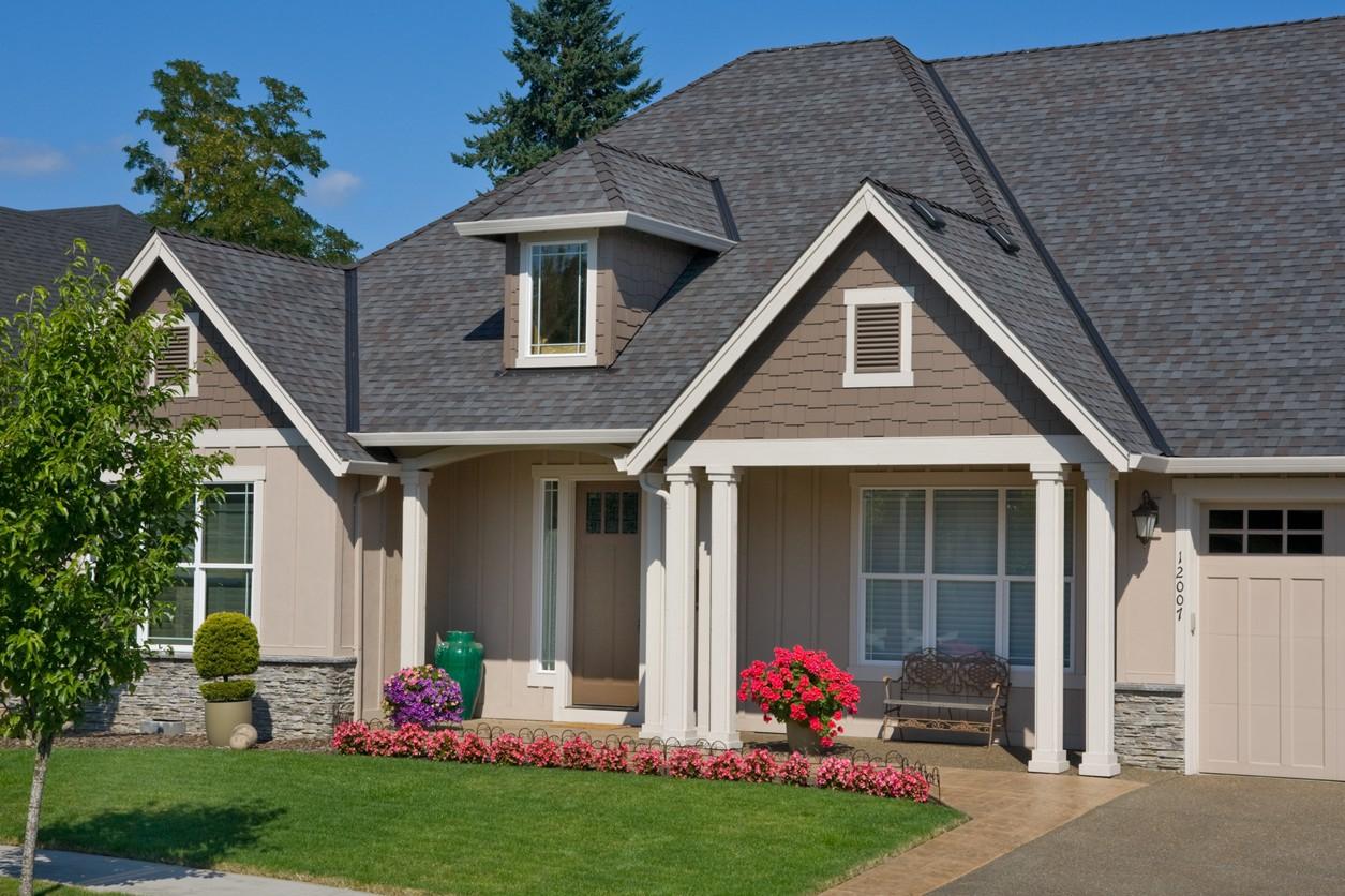 House plan exterior: Two-story home with dormers, gables, stone accents, covered entry, and attached garage.