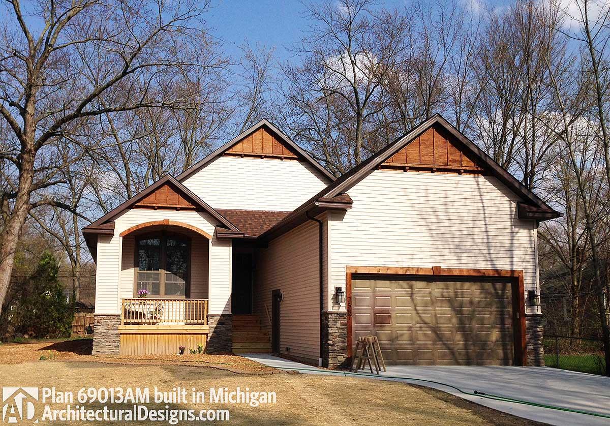 House plan exterior: Two-story Modern Farmhouse with gabled dormers, stone accents, wooden porch and garage door.