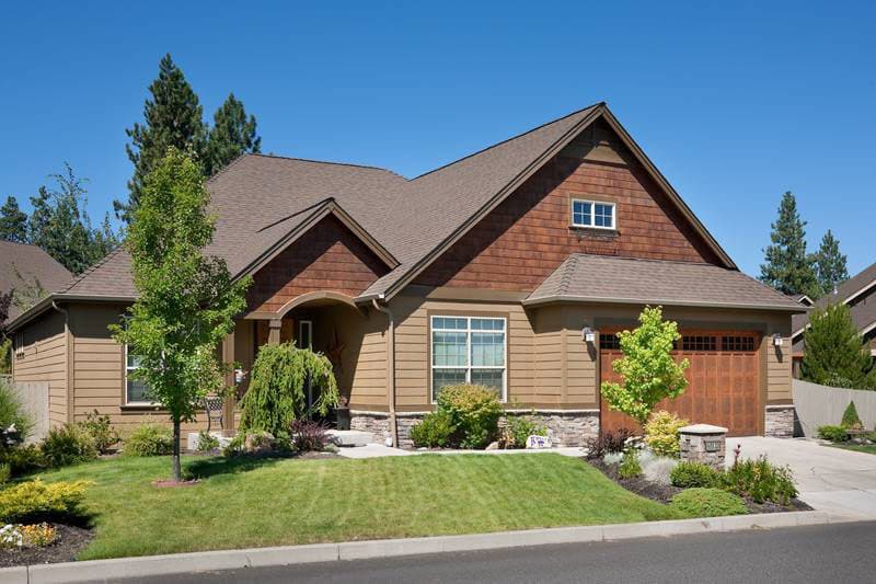 House plan exterior: This one-and-a-half-story home features a prominent gable with cedar shakes, arched entry, and a two-car garage.