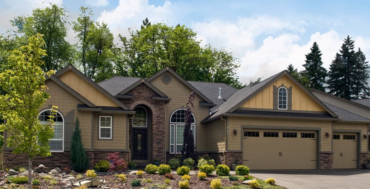 House plan exterior: One-story home with a mix of shake and stone siding, arched windows, and a three-car garage.
