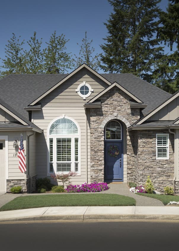 House plan exterior with stone accents, arched entryway, circular dormer, and a large arched window.