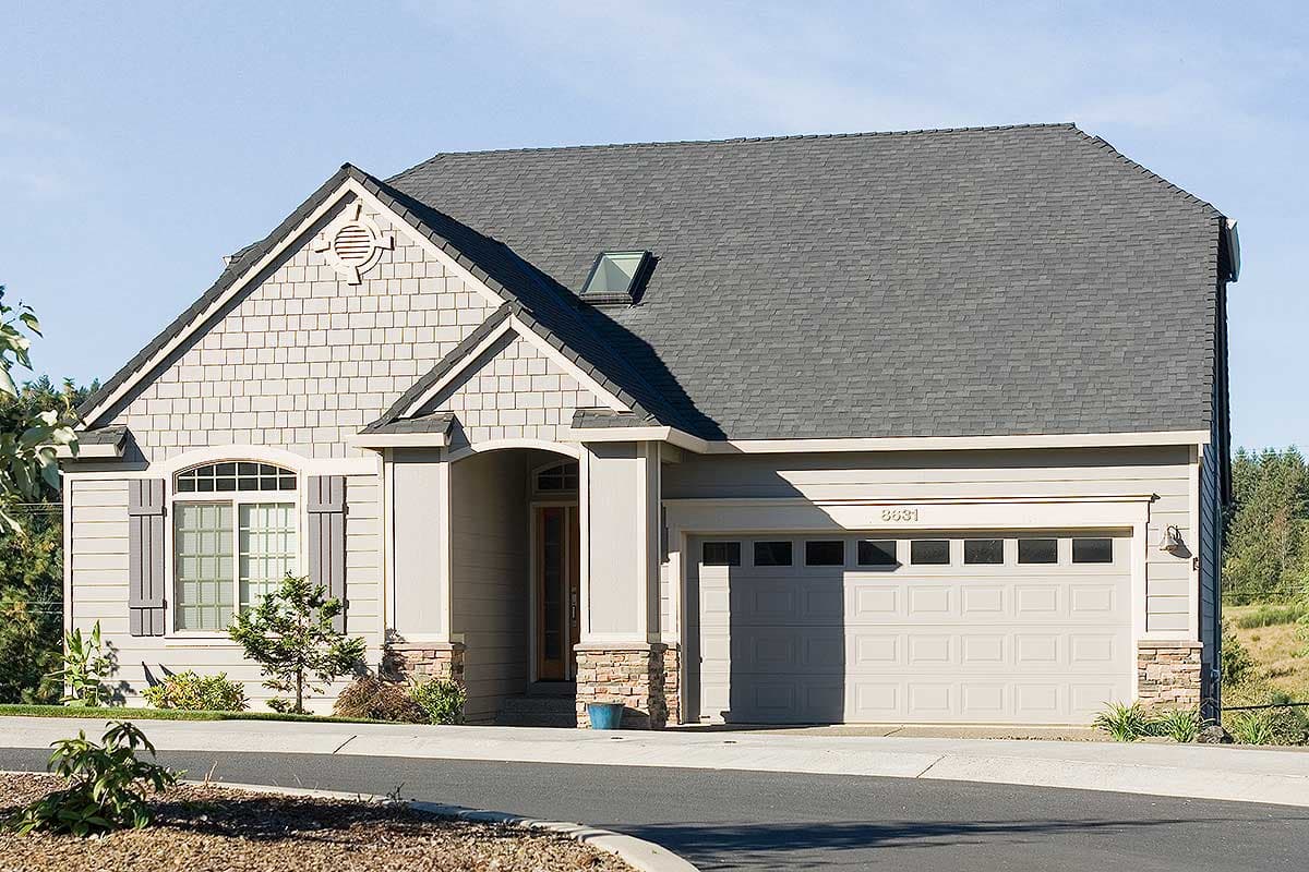 House plan exterior: Two-story, gray shingle siding, gabled roof with dormer, arched window, stone accents, and attached garage.