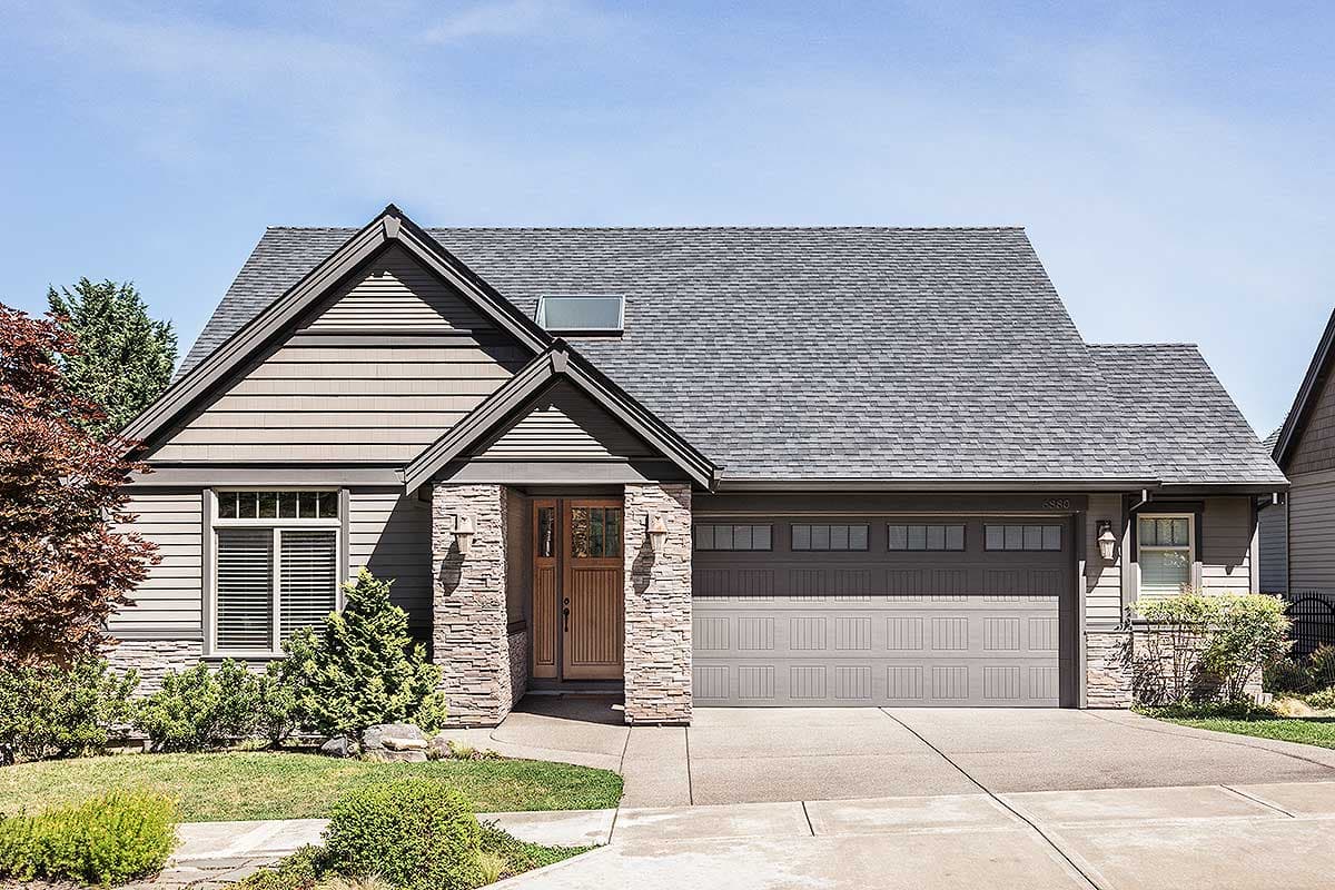 House plan exterior. Craftsman style, single-story house. Features a gable roof, stone facade, and attached garage with a multi-paneled door.