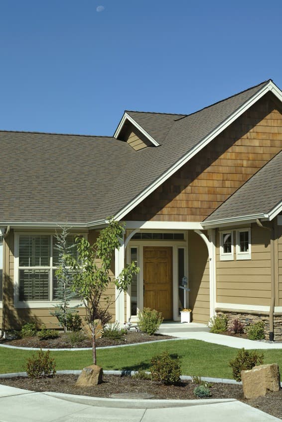 House plan exterior featuring a wood-shingled gable, arched entryway with a wood door, and multi-story rooflines.