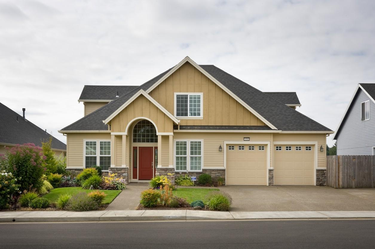 House plan exterior of a two-story home with a prominent arched entryway, gable accents, and a triple-bay garage.
