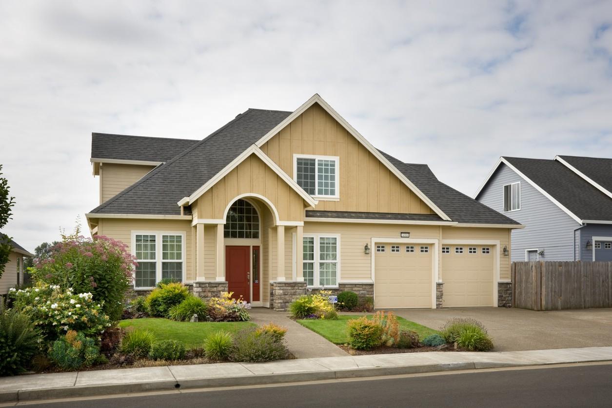 House plan exterior: Two-story home with a gabled roof, arched entryway, stone accents, and a three-car garage.