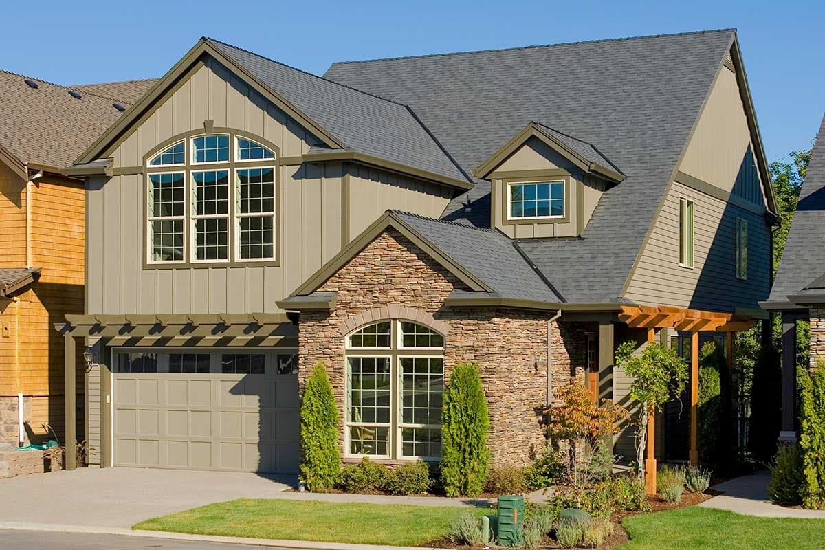 House plan exterior: Two-story home with stone accents, arched windows, board and batten siding, and attached garage with pergola.