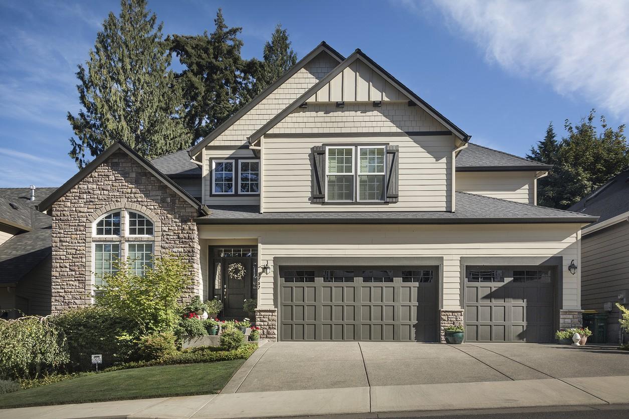 House plan exterior: Two-story home with stone accents, gabled dormers, front-facing three-car garage, and covered entry.