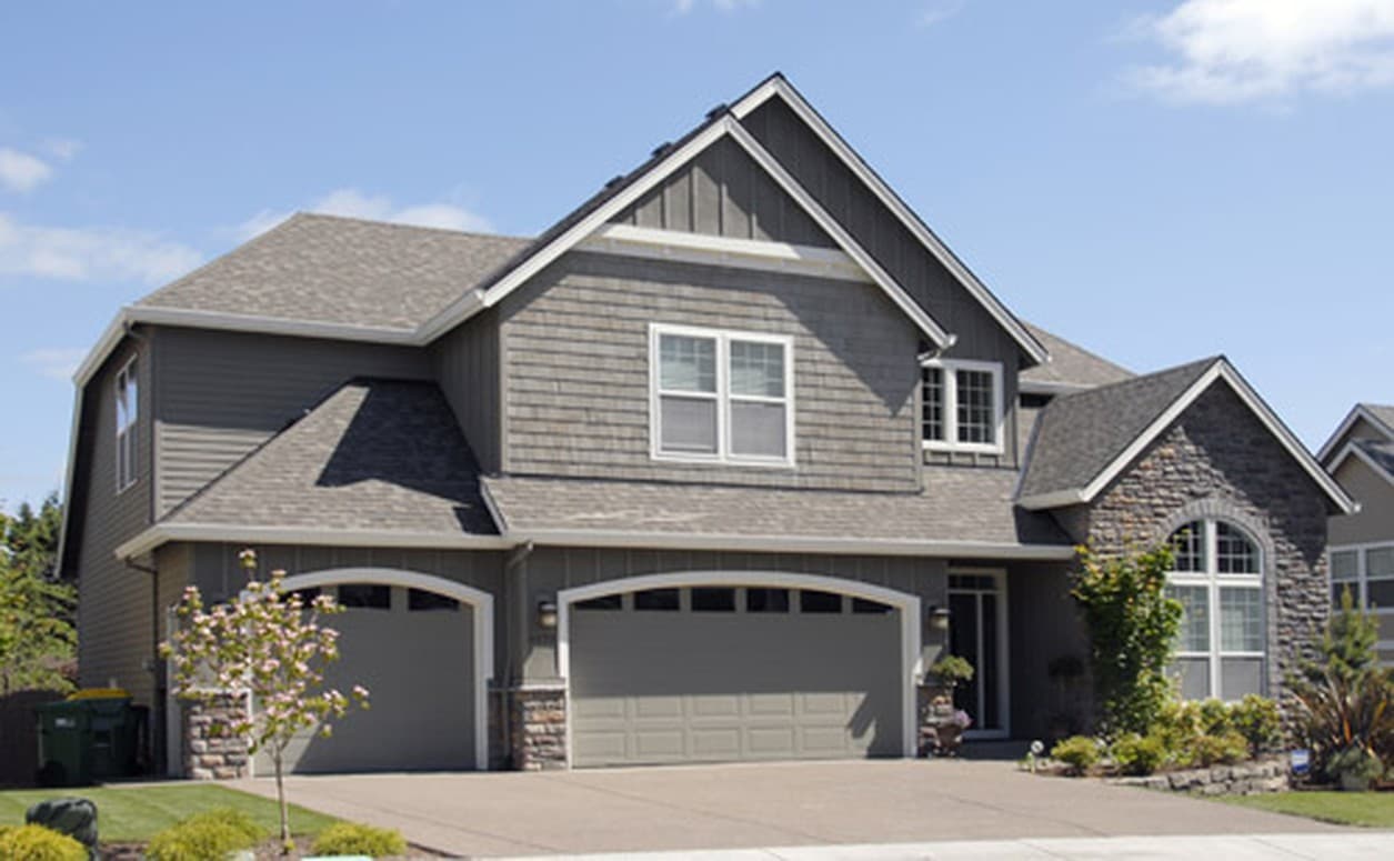 House plan exterior: Two-story home with dual garage doors, stone accents, gables, and stacked siding.