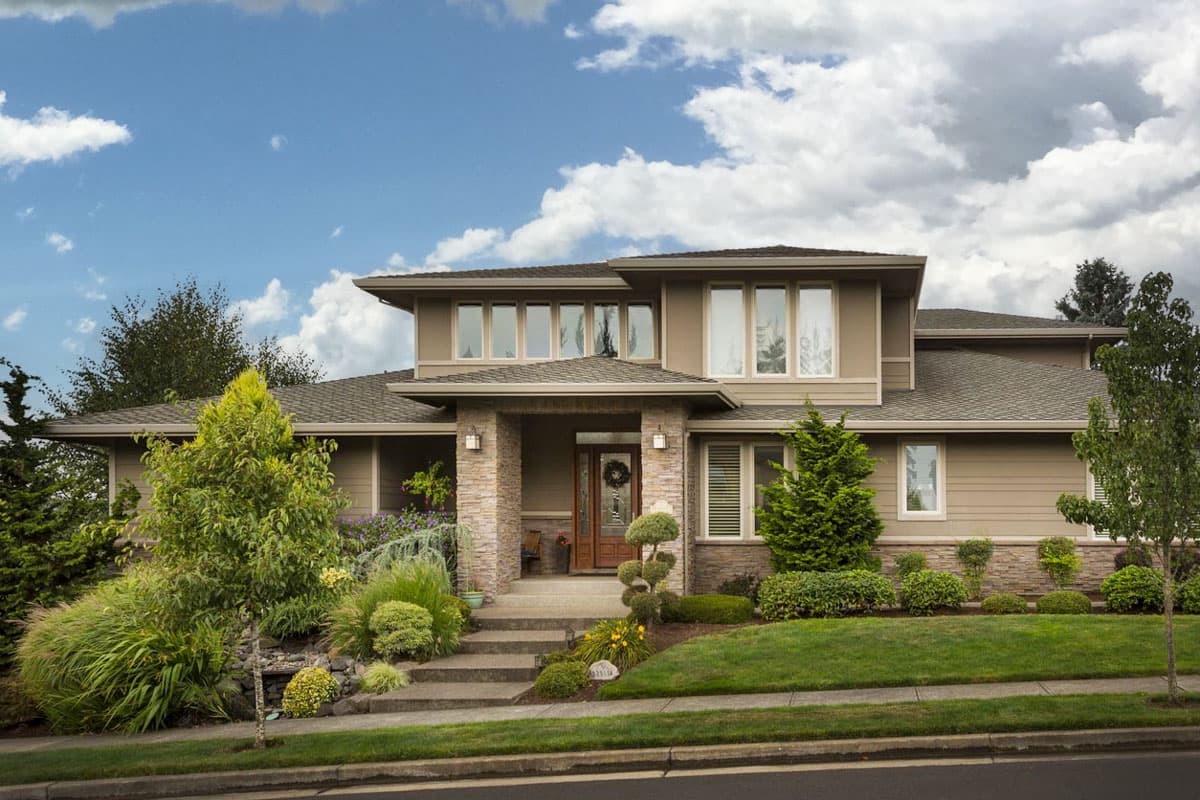 House plan exterior. Two-story home in a contemporary style with a flat roof, stone accents, and a covered front entry porch.