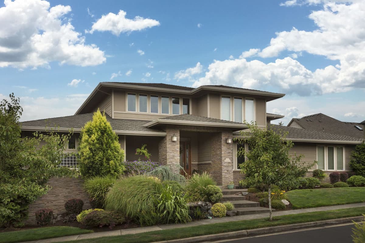 Modern house plan exterior with stacked stone entrance, multi-level rooflines, and large windows.