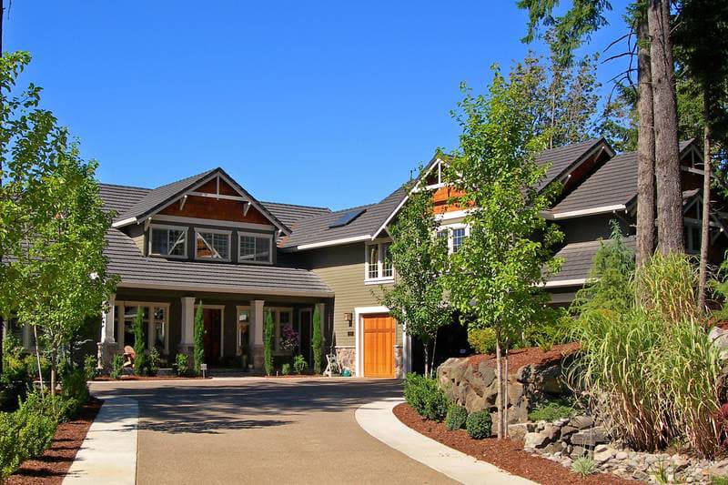 House plan exterior: Two-story home with gabled dormers, covered front porch supported by columns, and a side-facing garage.