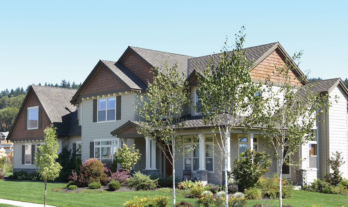 House plan exterior: Two-story home with steeply pitched gables, shingle siding, dormers, and covered front porch.