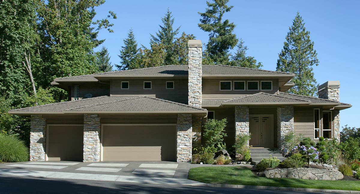 Modern house plan exterior with three-car garage, stone chimney, covered entry, and multiple rooflines.