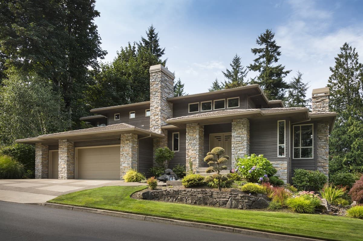 Modern house plan exterior with stone accents, a low-pitched roof, expansive windows, and a two-car garage.