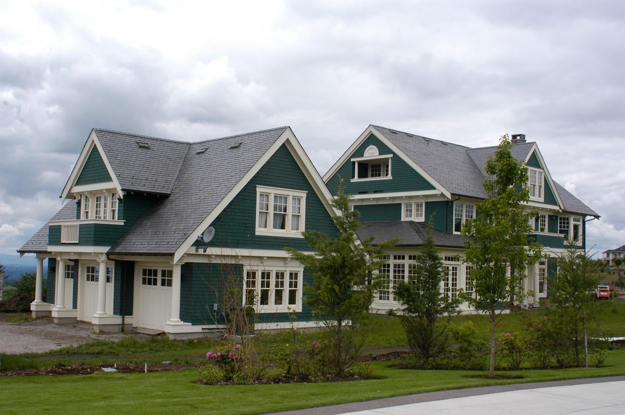 House plan exterior of a two-story green home with gables, dormers, white trim, and a three-car garage.
