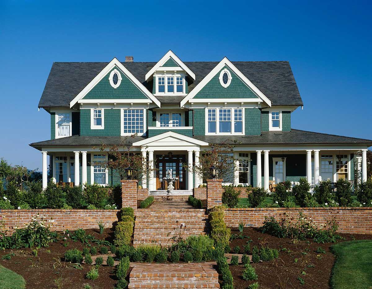 Craftsman style house plan exterior with a wrap-around porch, multiple gables, dormer windows, and prominent brick entryway.