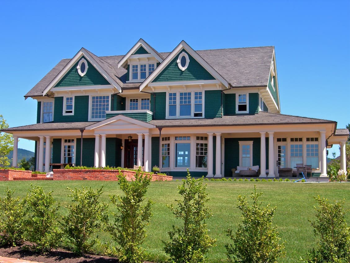 House plan exterior: Two-story Colonial Revival with wraparound porch, multiple gables, dormers, and white columns.