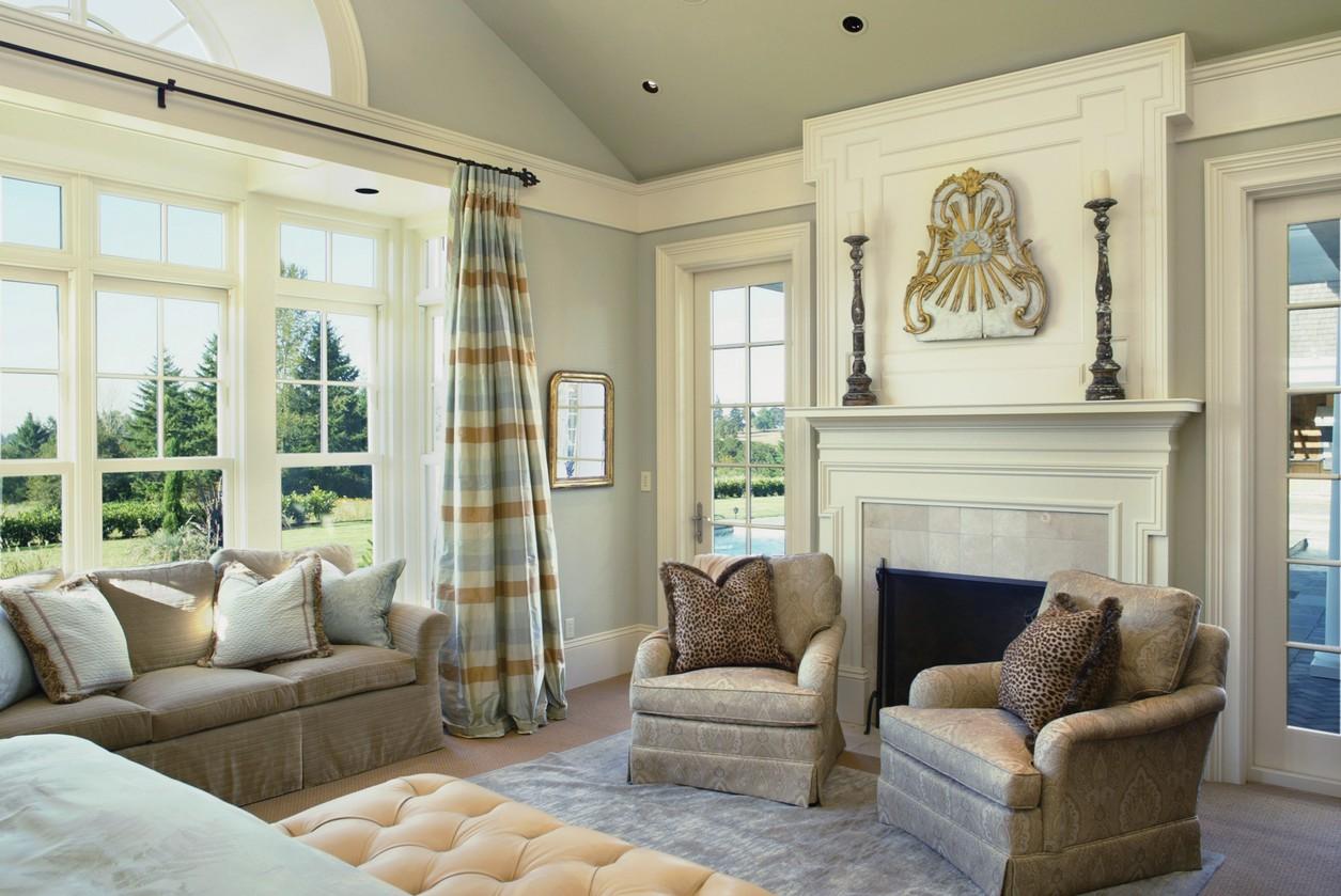 Living room with fireplace, large windows with pastoral view, and two upholstered chairs.
