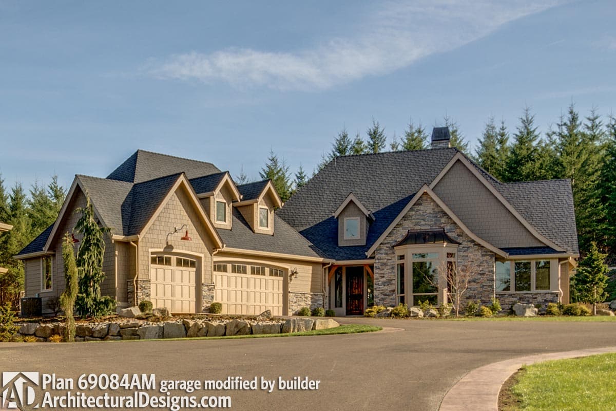 House plan exterior with stone accents, multiple gables, dormers, and a two-car garage. Features a steeply pitched roof.