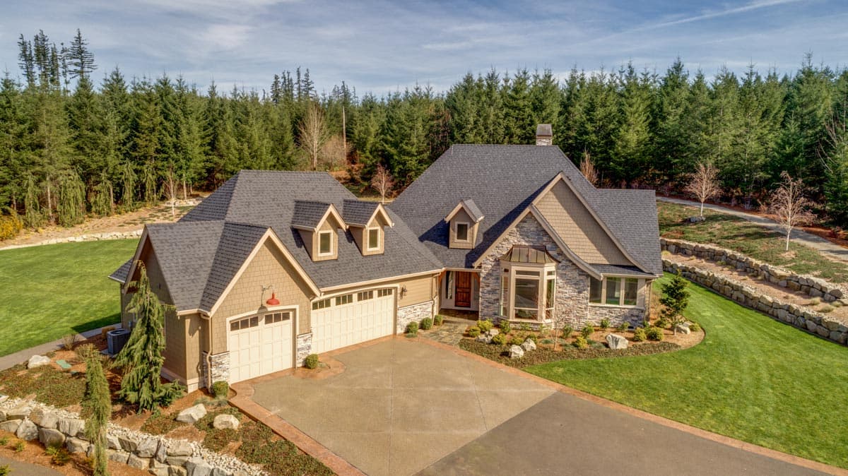 House plan exterior: Two-story home with stone accents, dormers, and a side-facing garage.