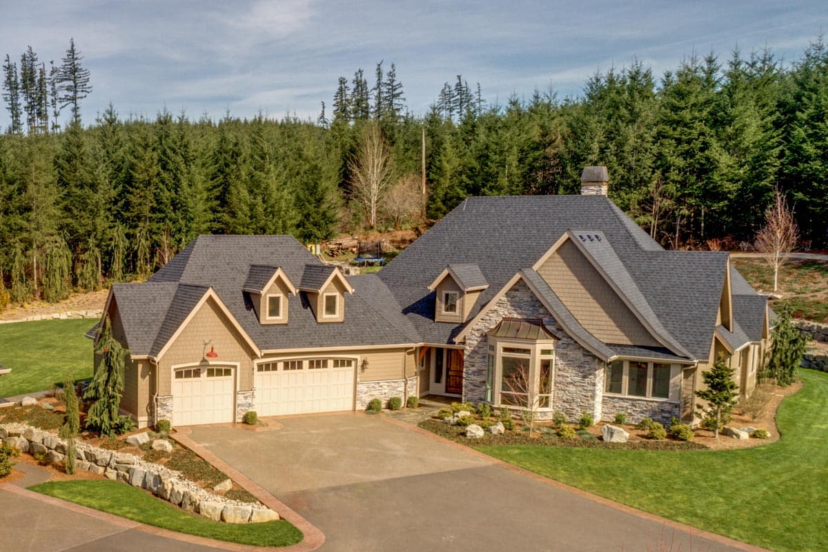 House plan exterior: Two-story Modern Farmhouse with side-entry garage, dormers, stone accents, and bay window.
