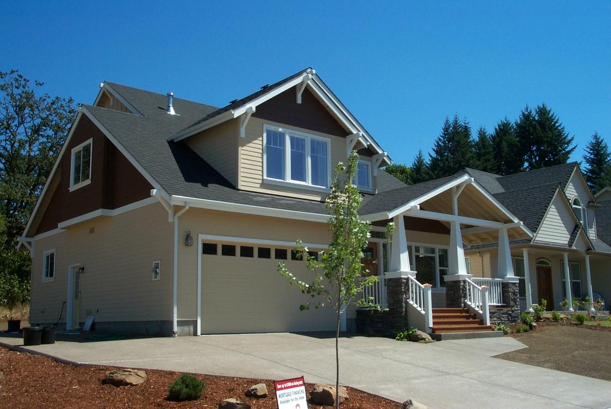 House plan exterior featuring a two-story home with a gabled roof, dormers, covered porch, and a two-car garage.