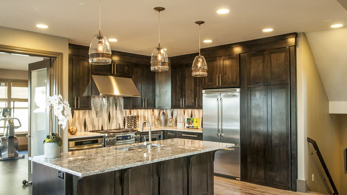 Kitchen featuring dark wood cabinets, granite island, stainless steel appliances, and a decorative tile backsplash.