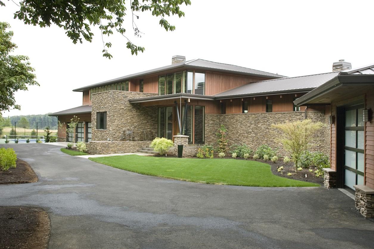 Modern house plan exterior with stone facade, wood siding, metal roof, and glass garage doors.