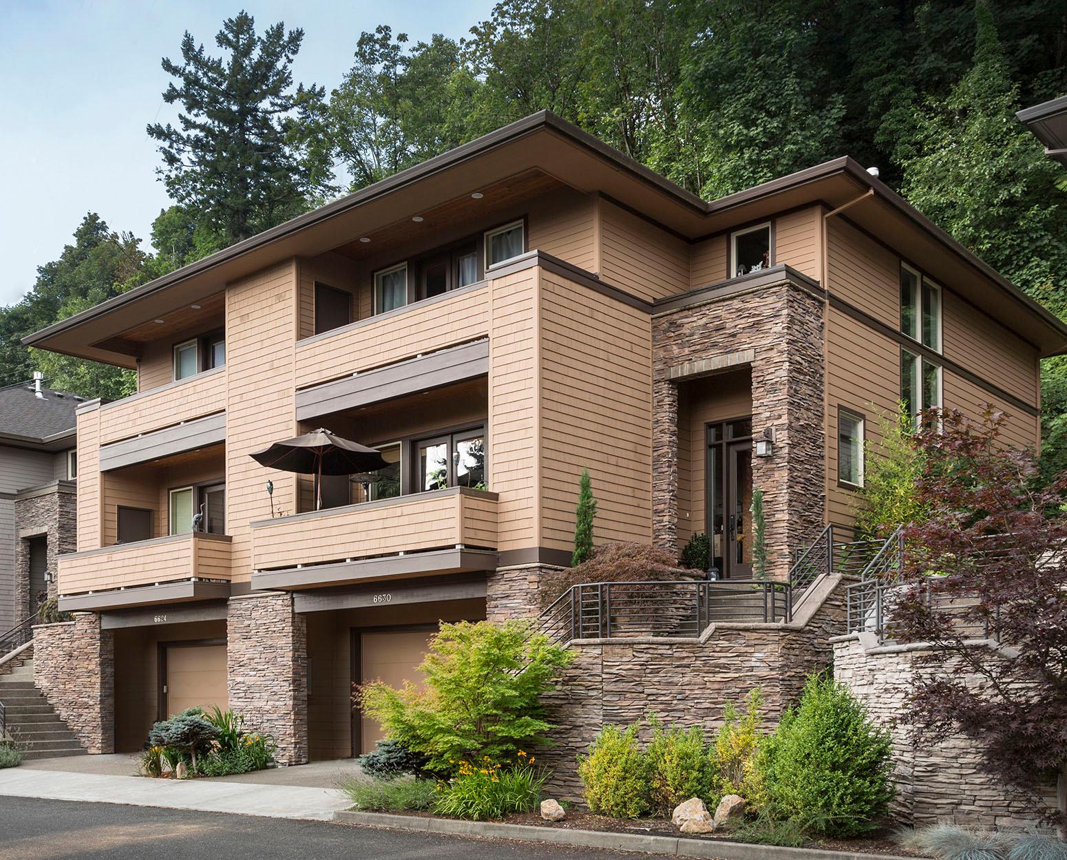 Modern house plan exterior with stacked stone base, multiple levels, balconies, and garage entrances.