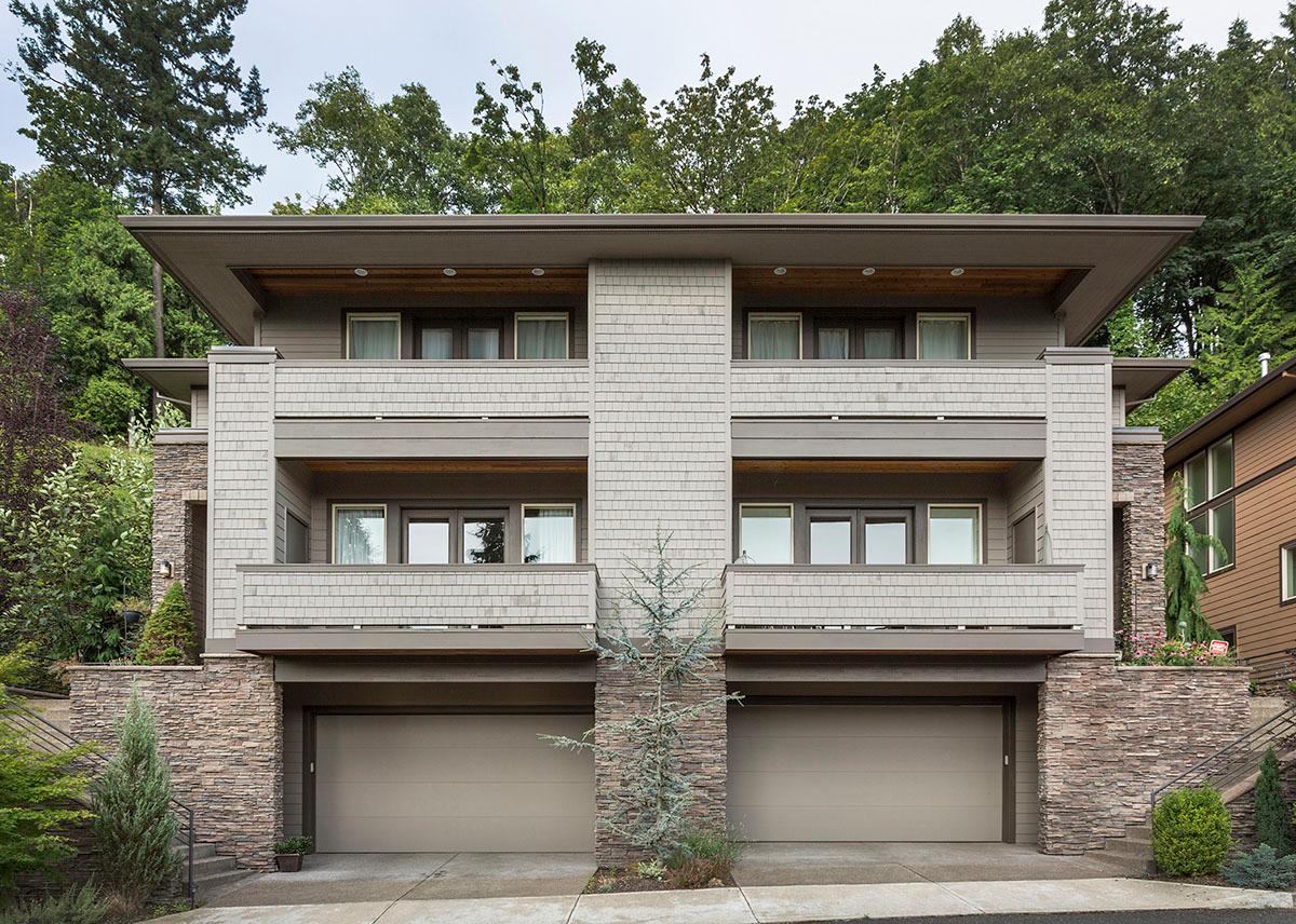 Modern multi-story house plan exterior with stacked stone accents, twin garages, balconies, and layered rooflines.