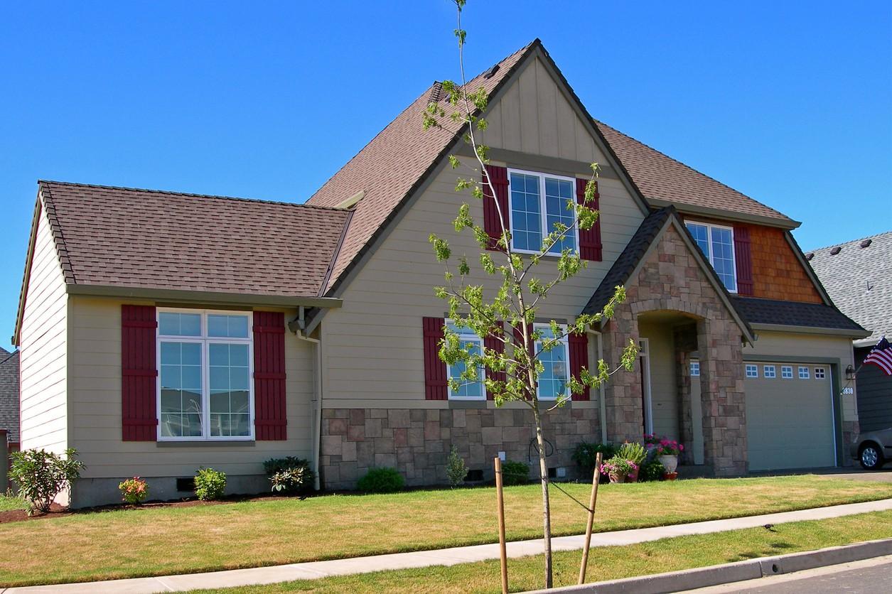 House plan exterior: Two-story home with stone accents, gabled roof, dormer windows, and side-entry garage.