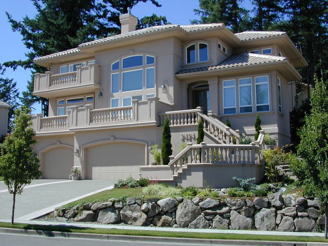 House plan exterior: Two-story stucco home with multiple balconies, a grand staircase, and a three-car garage.