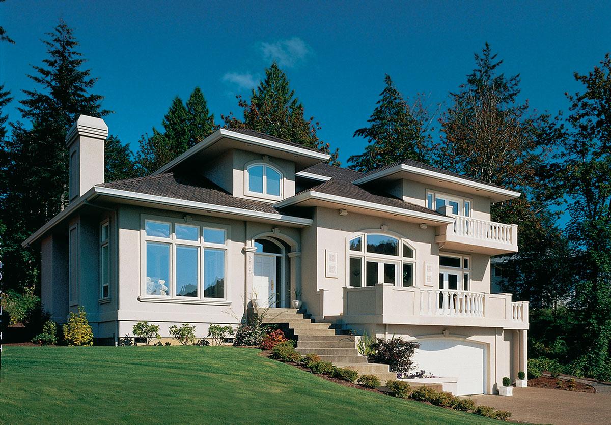 House plan exterior: Two-story stucco home with stucco chimney, arched windows, balconies, and attached garage.