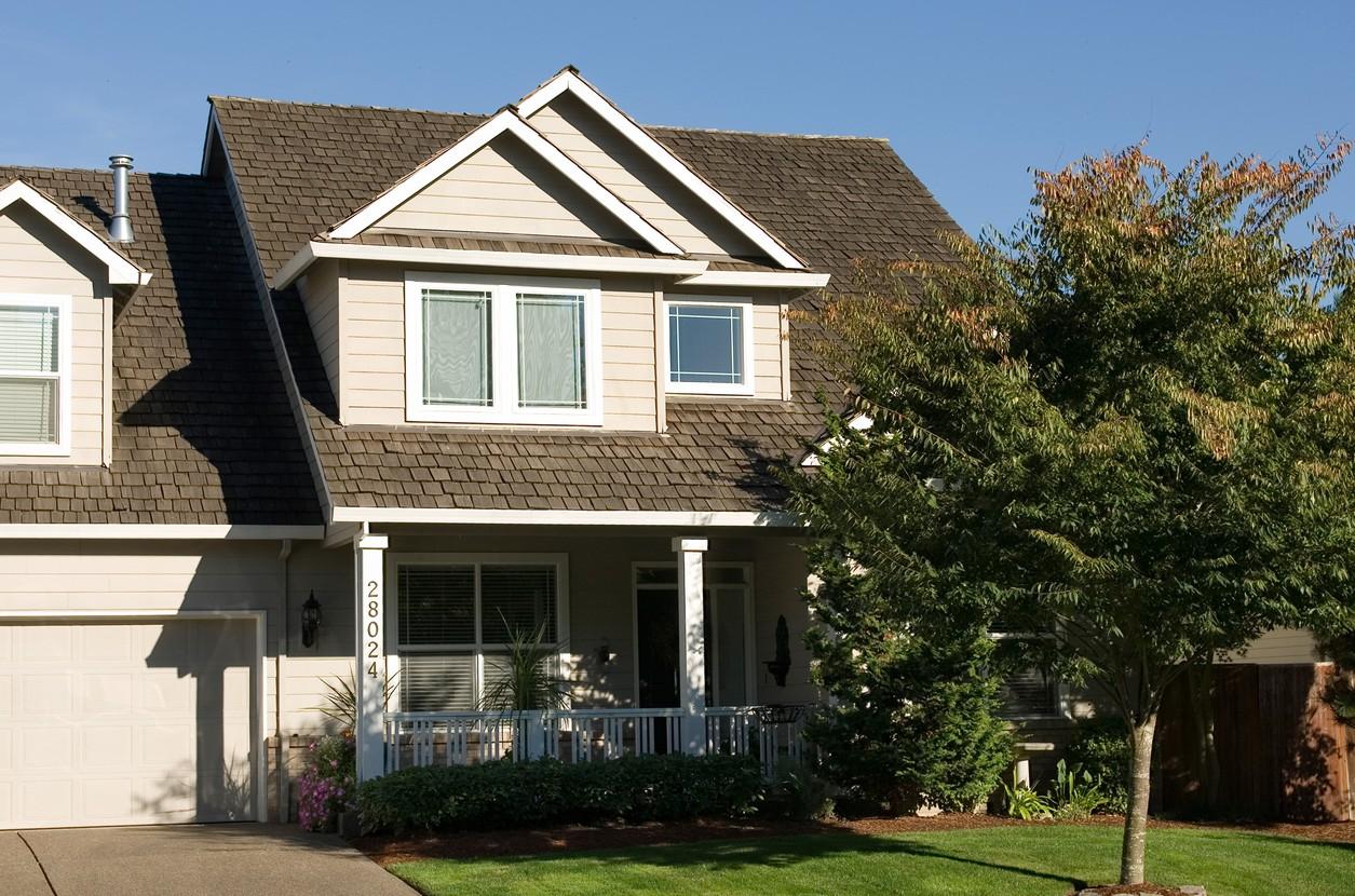 House plan exterior of a two-story home with a covered front porch, gables, and a shingled roof.